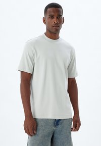 Lys grå kortærmet t-shirt lavet af blødt stof, med en rund halsudskæring og en afslappet pasform. Minimalistisk design uden synlige mønstre.