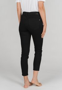 Zwarte skinny jeans met een getailleerd ontwerp, gemaakt van denim. Kenmerken zijn onder andere een middelhoge taille, vijf zakken en gestikte details.
