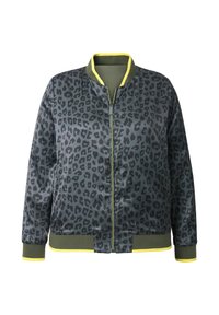 Bomberjacka i mörkgrå med svart leopardmönster, med en grön krage och manschetter, samt en gul accent på nederkanten och manschetterna.