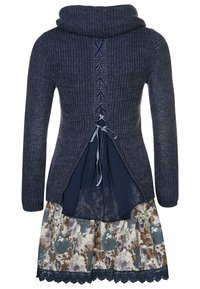 Marine gebreide trui met colhals, open rugdetail met lintkant, gelaagd over een rok met bloemmotief en kantzoom.