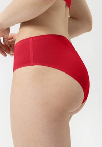 Czerwony bikini z wysokim stanem, wykonane z gładkiego, elastycznego materiału. Posiada czyste wykończenie bez widocznych szwów, podkreślające prosty design.