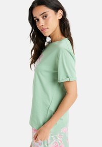 Mintgrøn kortærmet t-shirt med et blomsterdesign i pink. Fremstillet af blødt stof med opkrøllede manchetter og en klassisk pasform.