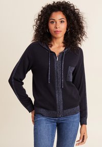 Felpa con zip blu navy, caratterizzata da un fronte testurizzato, pannelli laterali lucidi a contrasto, tasca anteriore e cappuccio con cordino. Tessuto morbido e lavorato a maglia.