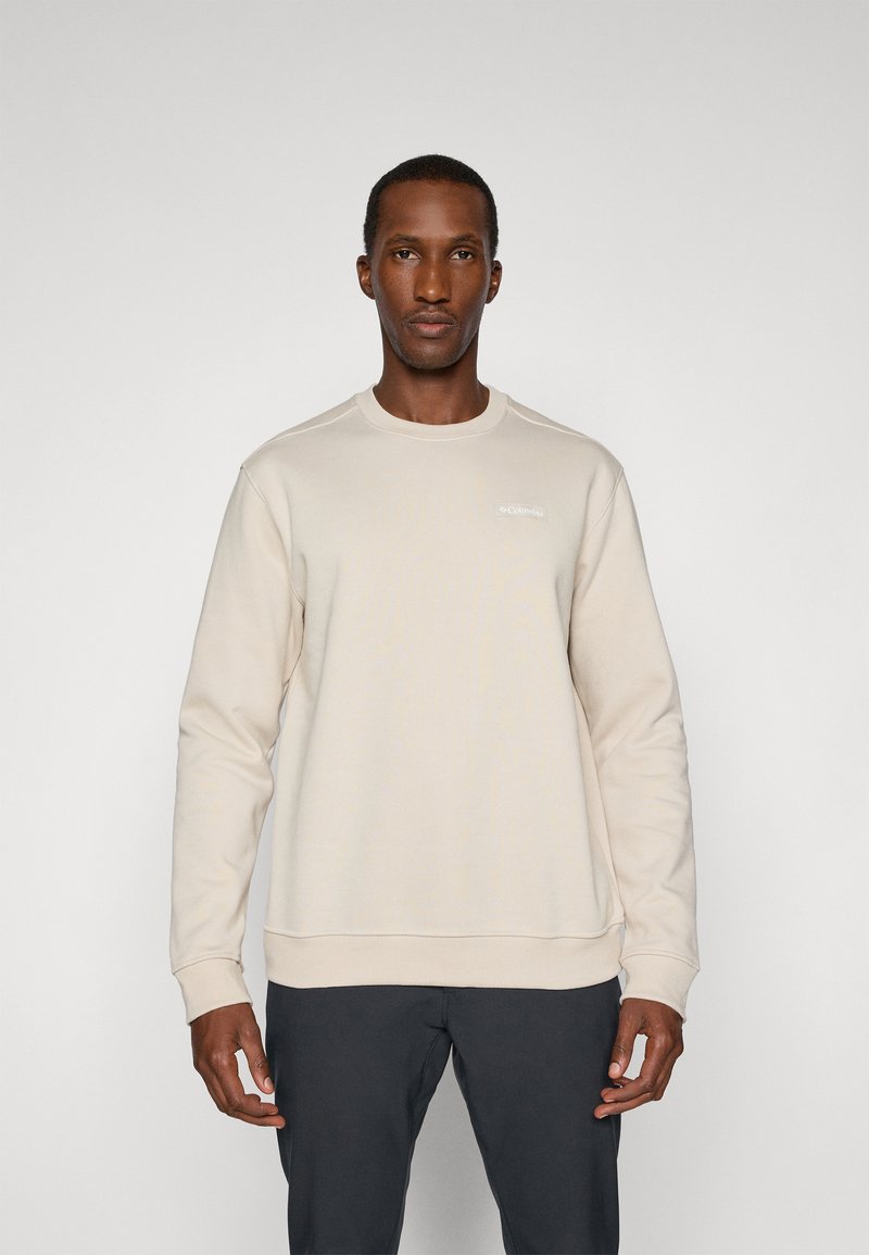 Sweatshirt bege com um decote redondo, mangas longas, punhos e bainha canelados, com um logótipo subtil no peito. Textura suave.