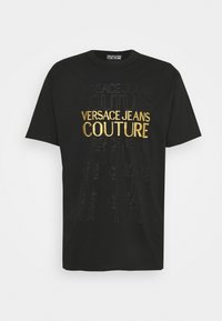 Schwarzes Baumwoll-T-Shirt mit geprägtem Textdesign "VERSACE JEANS COUTURE" in Gold und Schwarz, Kurzarm und Rundhalsausschnitt.