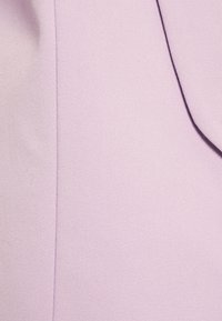 Světl lavenderový látka s hladkým, texturovaným povrchem a diagonálním tkaním. Obsahuje jemný lesk a viditelné detaily prošívání.