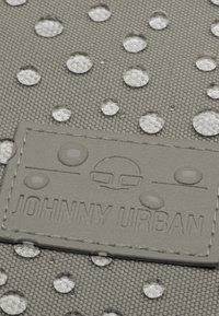 Šedá textúrovaná taška s jasnými vodnými kvapkami a obdĺžnikovou embosovanou nášivkou s nápisom "JOHNNY URBAN" na prednej strane.