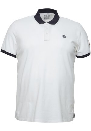 Valkoinen poolopaita, jossa on tummansininen kaulus ja hihansuut, kolmonen nappilista ja pieni brodeerattu maapallon logo vasemmalla rinnalla. Puuvillasekoitekangas.