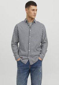Camisa de cuadros de botones para hombre en azul marino y blanco, de manga larga, con un ajuste casual, combinada con vaqueros azules. Diseño sencillo y moderno.