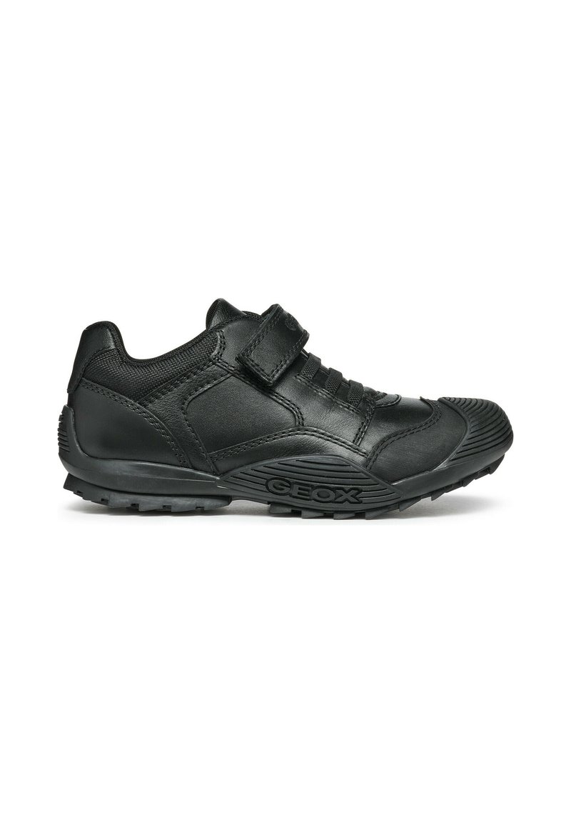 Zapatos Geox negros con parte superior de cuero texturizado, correa de Velcro, suela de goma y un patrón de agarre distintivo en la suela.