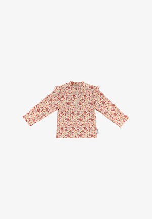Long-sleeve floral top in cream, featuring a ruffled shoulder, red and green flower patterns, and a front zipper detail.
