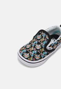 Czarne sneakersy wsuwane z kwiecistym wzorem, kolorowymi kwiatami i grafiką tygrysa, biała gumowa podeszwa i czarne wykończenia.