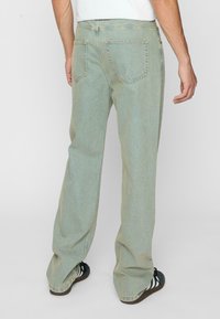 Světle zelené džíny z denimu s volným střihem, rovnými nohavicemi, designem s pěti kapsami a viditelnými švy na zadních kapsách.