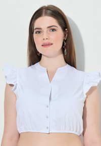 Blusa bianca cropped con maniche a campana arricciate, dotata di chiusura frontale con bottoni e orlo elasticizzato per un look aderente. Tessuto liscio.