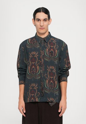 Button-up shirt featuring a dark fabric with a floral and paisley pattern in earthy tones. Long sleeves and a collared neckline.