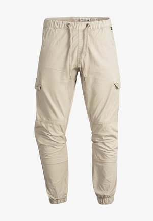 Beige cargobukser med elastisk talje og snøre. Har tilspidsede ben, sidelommer og syningsdetaljer på knæ og sømme.