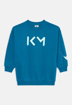 Sweatshirt teal com mangas longas, punhos canelados e decote redondo. Apresenta as letras "KM" em azul claro na parte da frente e um detalhe de logotipo na manga.