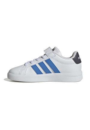 Baskets basses blanches avec des rayures bleues, languette de talon noire, lacets blancs et une bride Velcro sur le côté, vue de l'extérieur.