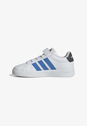 Baskets basses blanches avec des rayures bleues, languette de talon noire, lacets blancs et une bride Velcro sur le côté, vue de l'extérieur.