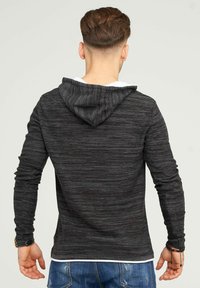 Dunkelgrauer Hoodie mit strukturiertem gestreiften Muster, ausgestattet mit einer Kapuze und einem weißen Innenfutter. Lange Ärmel und gerader Schnitt an der Taille.