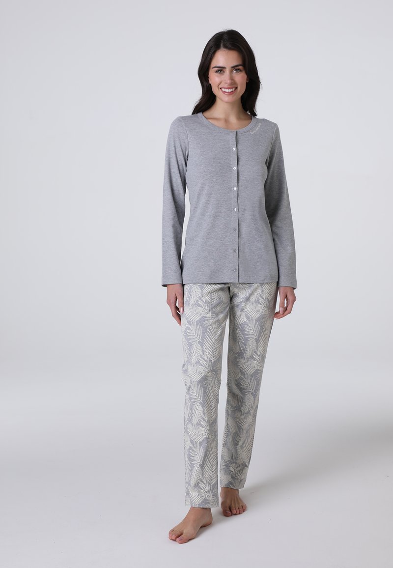 Maglietta grigia a maniche lunghe con chiusura a bottoni abbinata a pantaloni chiari a fantasia con design di foglie in tonalità di grigio e crema.