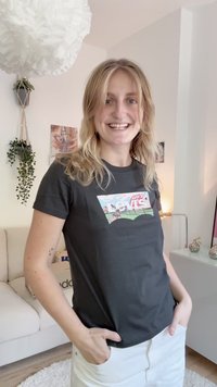 Čierne bavlnené tričko s grafickým logom v pastelových farbách. Má okrúhly výstrih a krátke rukávy, nosené s bielymi šortkami.