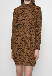 Hnědé šaty na knoflíky s leopardím vzorem, dlouhými rukávy a zavazovacím páskem v pase pro nastavitelnou velikost.