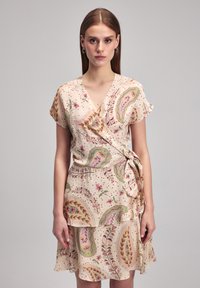 Kurzes, ärmelloses Wickelkleid aus weichem, beigem Stoff mit floralen Paisleymustern. Verfügt über einen gerafften Saum und eine Seitenschnürung für eine figurbetonte Silhouette.