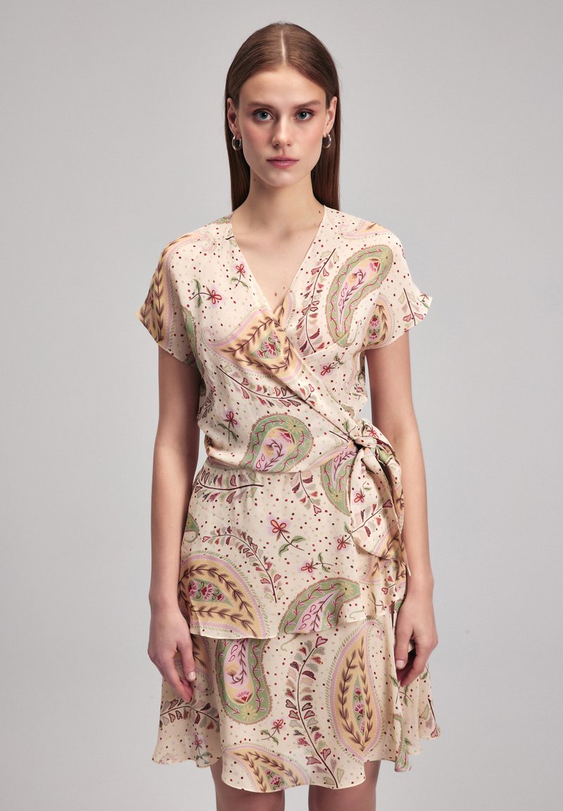 Kurzes, ärmelloses Wickelkleid aus weichem, beigem Stoff mit floralen Paisleymustern. Verfügt über einen gerafften Saum und eine Seitenschnürung für eine figurbetonte Silhouette.