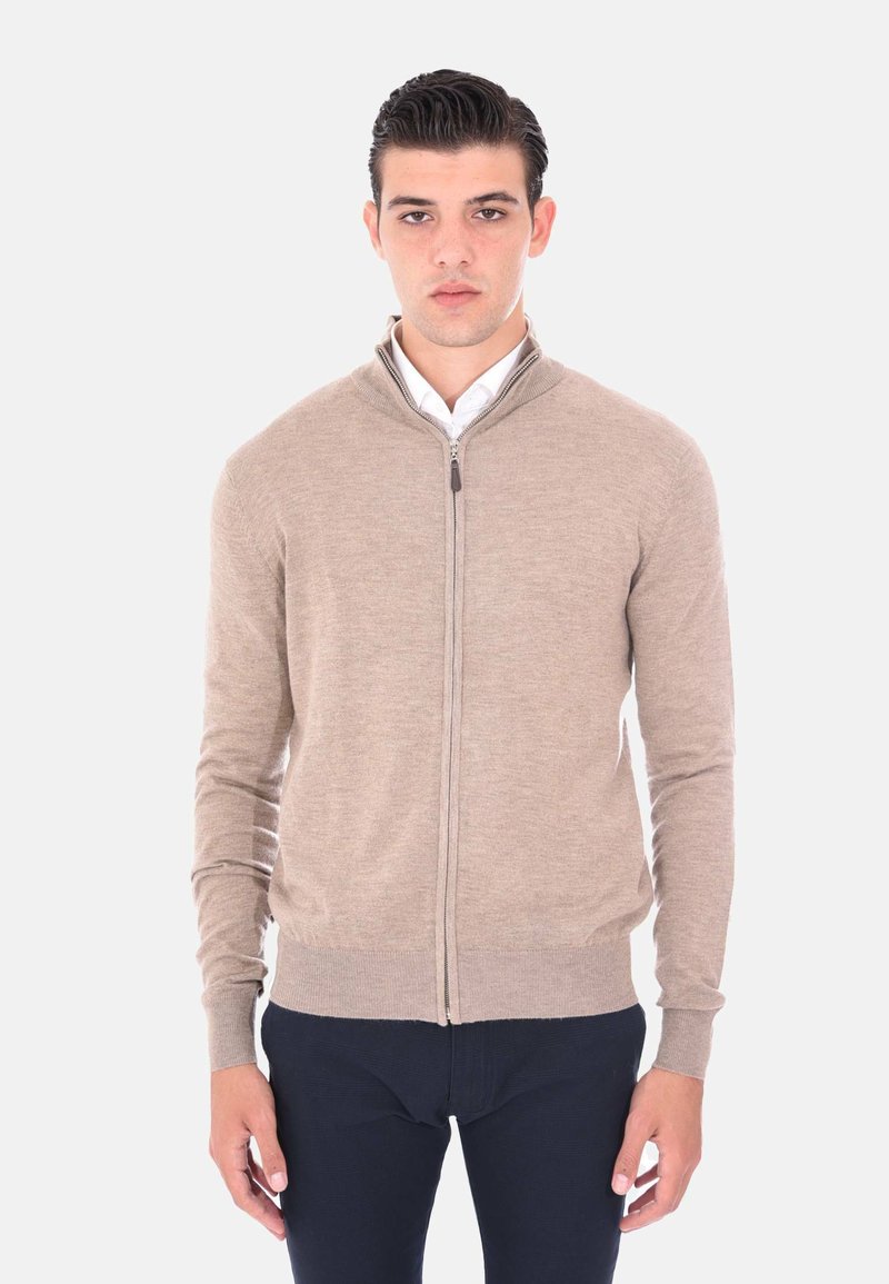 Cardigan beige con zip realizzato in tessuto morbido; presenta un colletto alto, maniche lunghe e polsini e orlo a coste per un look aderente.