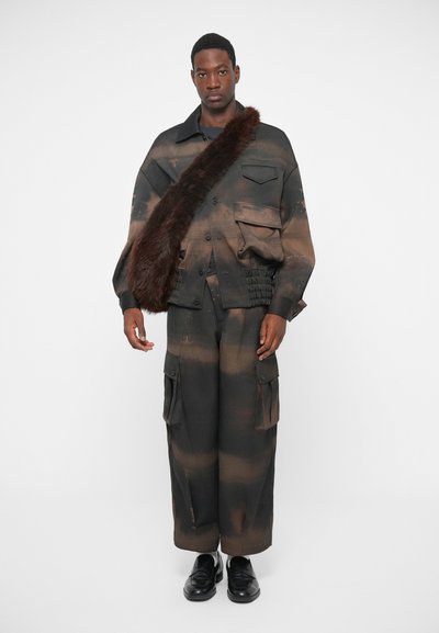 Ensemble de mode comprenant une veste à motifs marron et noir avec poches, associée à un pantalon cargo large assorti. Accentué par de la fourrure synthétique.