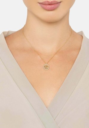 Gold pendant necklace with a circular charm and intricate design, accented with small stones, hung on a delicate chain.