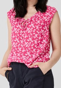 Top corto de manga corta floral en color rosa con un escote redondeado y un pequeño detalle de lazo. Tejido ligero con un corte holgado y una superficie ligeramente texturizada.