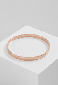 Roosa kuldne bangle-käevõru sileda ja poleeritud viimistlusega, mille sisepinnal on graveeritud lause "SEISATA JA LÕHNAJAA ROSE".