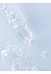 Klar væske med bobler, lys blå baggrund, der har forskellige størrelser af transparente kugler og en smal, lang glasdråber.