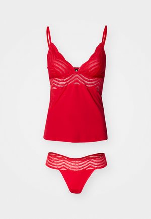 Ensemble de lingerie rouge comprenant un camisole avec des bretelles réglables et des détails en dentelle, associé à un string assorti avec un bord en dentelle.