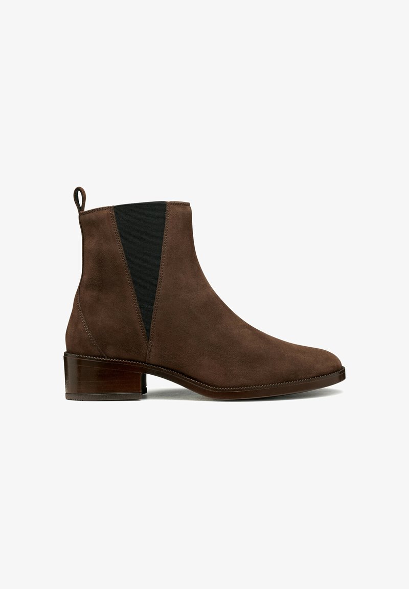 Bottines en suède marron avec des panneaux latéraux élastiques, une languette et un petit talon empilé. Texture lisse avec un design minimaliste.