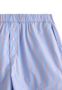 Lyseblå shorts med lodrette orange striber, elastisk talje og knaplukning. Bomuldsstof, glat tekstur og sidelommer.