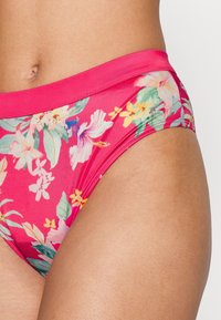 Parte de baixo de biquíni floral com uma faixa na cintura rosa, apresentando um padrão tropical de hibiscos e folhas em tons de verde, amarelo e rosa.