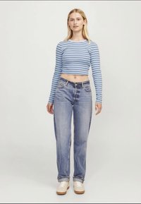 Top cropped de manga longa às riscas azul claro e brancas, combinado com jeans straight-leg de lavagem clara e ténis beges. Design simples e casual.