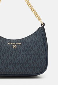 Navy-mönstrad axelväska med guldkedja. Har Michael Kors-logotyp och textil med en subtilt sammanflätad MK-design.