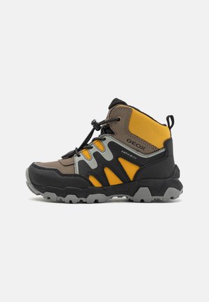 Kindlicher hoher Wanderschuh in Braun, Schwarz und Gelb, mit dicker Profilsohle und verstellbaren elastischen Schnürsenkeln.