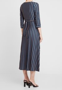 Robe rayée bleu marine avec des manches trois-quarts, taille cintrée et ceinture à nouer. Présente des fines lignes verticales de différentes couleurs.