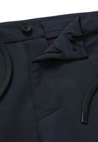 Dark blue athletic pants featuring a button closure, braided drawstring, and zippered pocket. Smooth fabric with minimal seams.