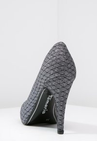 Escarpin pailleté noir avec un bout pointu et un talon aiguille. Le tissu texturé présente un motif géométrique. L'intérieur affiche le logo de la marque et la taille.