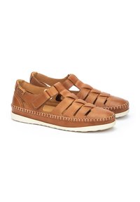 Sandalias de cuero marrón con parte superior perforada, dos tiras ajustables y suelas de goma blanca. Presenta costuras de contraste a lo largo de los bordes.