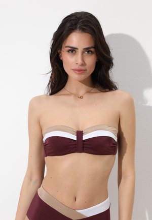 Donna con capelli lunghi e scuri che indossa un top bikini senza spalline color bordeaux, bianco e beige con slip abbinato, su sfondo bianco.