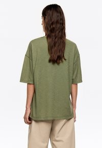 Olijfgroene oversized T-shirt van zacht materiaal, met korte mouwen, een relaxte pasvorm en een ronde hals.