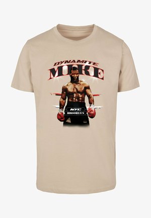 Beige kokvilnas t-krekls ar grafisku attēlu, kurā redzams bokseris ar tekstu "DYNAMITE MIKE", sarkanām akcentiem un melniem cimdiem.