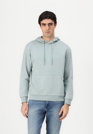 Light green hoodie made of soft fabric, featuring a front pocket, drawstring hood, and a small logo on the chest. Worn with blue jeans.